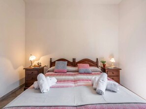 A neatly made bed with pillows and a blanket, two bedside tables with lamps, and a small potted plant on one table. - Cozy Home Near the sea (Siniscola)