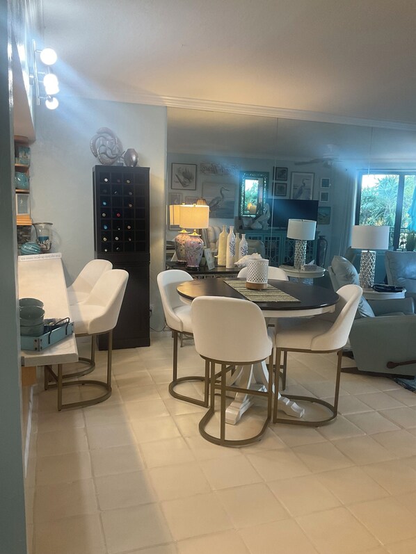 Un coin repas avec une table ronde, des chaises blanches et un buffet noir doté de plusieurs compartiments.