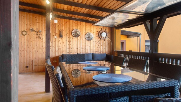 An outdoor seating area with a wooden ceiling, wicker furniture, and decorative wall plates. - Apartment on the Main 1 with Private Terrace (Gemünden am Main)