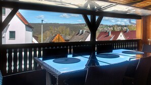 A covered outdoor seating area with a view of houses and trees. - Apartment on the Main 1 with Private Terrace (Gemünden am Main)