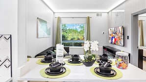 A modern hotel room with a dining area featuring black and green tableware, a potted orchid, and a snack jar. - 1 bedroom apartment near Disney and Universal (Orlando)