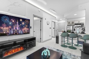 Ein modernes Wohnzimmer mit Flachbildfernseher, Kamin und Barbereich mit Hockern.