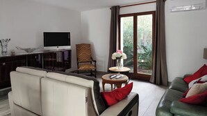 Uma sala de estar moderna com um sofá, uma televisão, uma poltrona e uma mesa com flores.