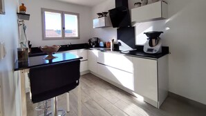 Cozinha moderna com armários brancos, bancada preta e janela que permite entrada de luz natural.