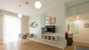 A modern living room with a flat-screen TV, a dining area with chairs, and a fireplace. - BDC - Tender 2Bdr apartment @Navigli area (Milan)