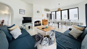 Una sala de estar moderna con televisor, sofá y comedor.