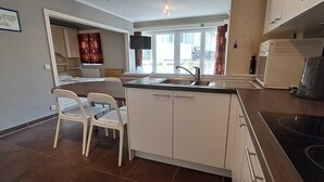 Eine kompakte Küche mit Essbereich, Backofen und großem Fenster für natürliches Licht.