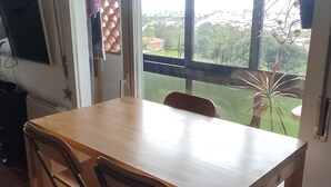 Un comedor con una mesa y sillas de madera, un ventilador de techo y vistas al exterior a través de amplias ventanas.