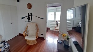 Un salón con sofá, sillón, una obra de arte colgada en la pared y suelo de madera.