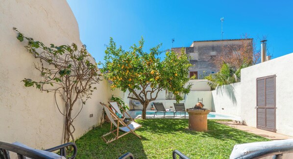 Ein Garten mit Pool, Baum und Stuhl.