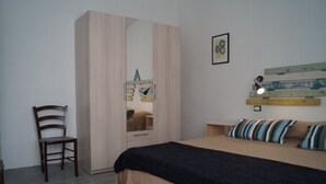 A bedroom with a bed, a chair, a wardrobe, and a mirror. - Sa Domo de Mannoi, home just minutes from Sardinia's most beautiful beaches (Orosei)