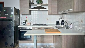 Eine moderne Küche mit Kühlschrank, Herd, Spüle und Holzschränken.