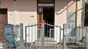 Ein begrenzter Zugang zu einem Gebäude mit nummerierten Türen, einem Briefkasten und einem Willkommensschild.