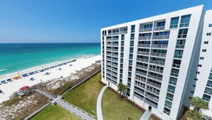 A high-rise hotel with multiple balconies, a beach view, and a well-maintained lawn. - Beachfront Views from ST 1104 with Free Beach Service for 2! (Destin)