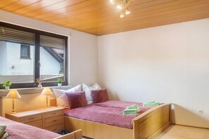 Une chambre à coucher avec un lit, des tables de chevet, des lampes et une fenêtre avec des stores.