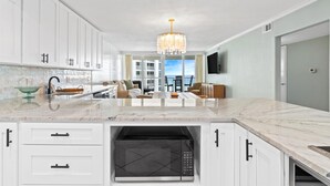 A modern kitchen with white cabinetry, a central island, and a built-in microwave. - Gorgeous ST 2073 w/Beach Service (Destin)