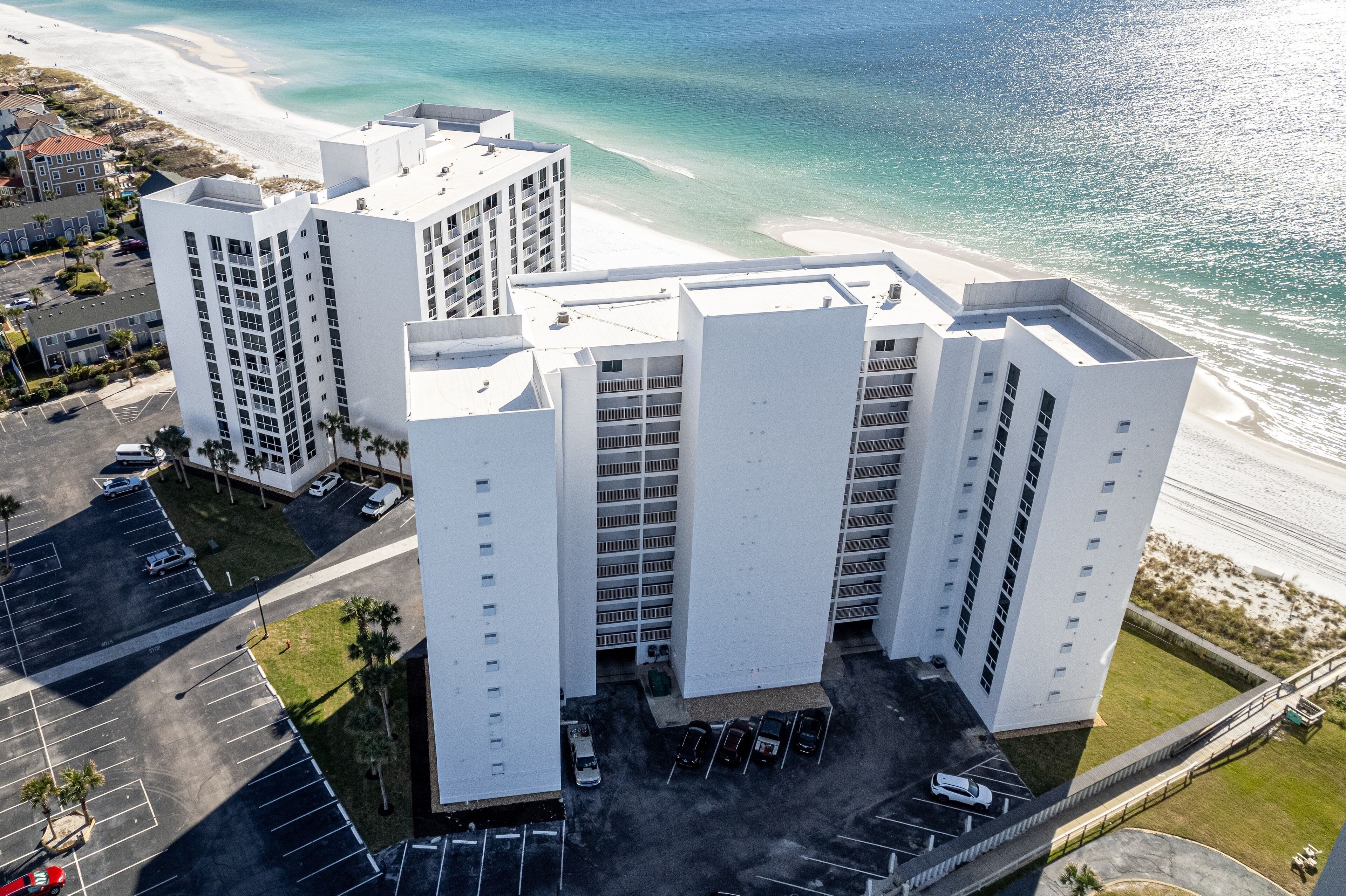 Ein Hochhaus mit mehreren Etagen, einem Parkplatz und Blick auf den Strand.