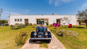 A vintage car parked in front of a modern house with a paved driveway. - Apartment 'Core Resort - 1' with Wi-Fi and Air Conditioning (Tuglie)
