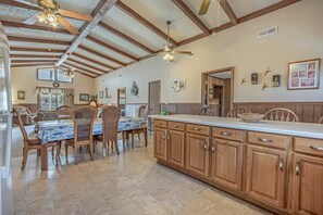 A spacious kitchen with wooden cabinets, a dining area with a table and chairs, and a ceiling fan. - Loafers Lodge - Channel Home (North Myrtle Beach)
