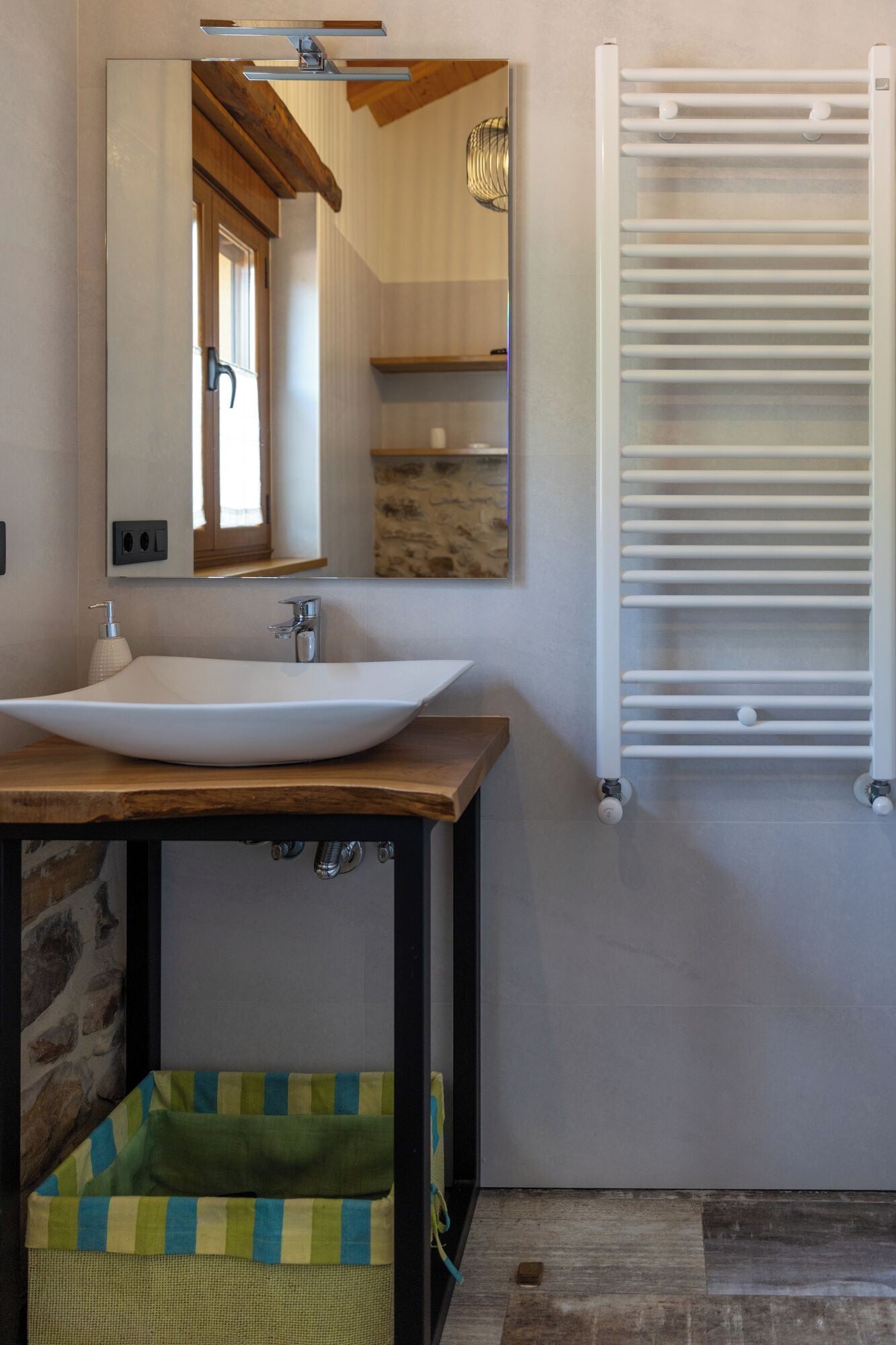 A bathroom with a white sink, a mirror, a towel rack, and a stone shelf.