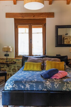 A bedroom with a bed, a window, a lamp, and a mirror. - El Refugio II de Verdiago (Cremenes)