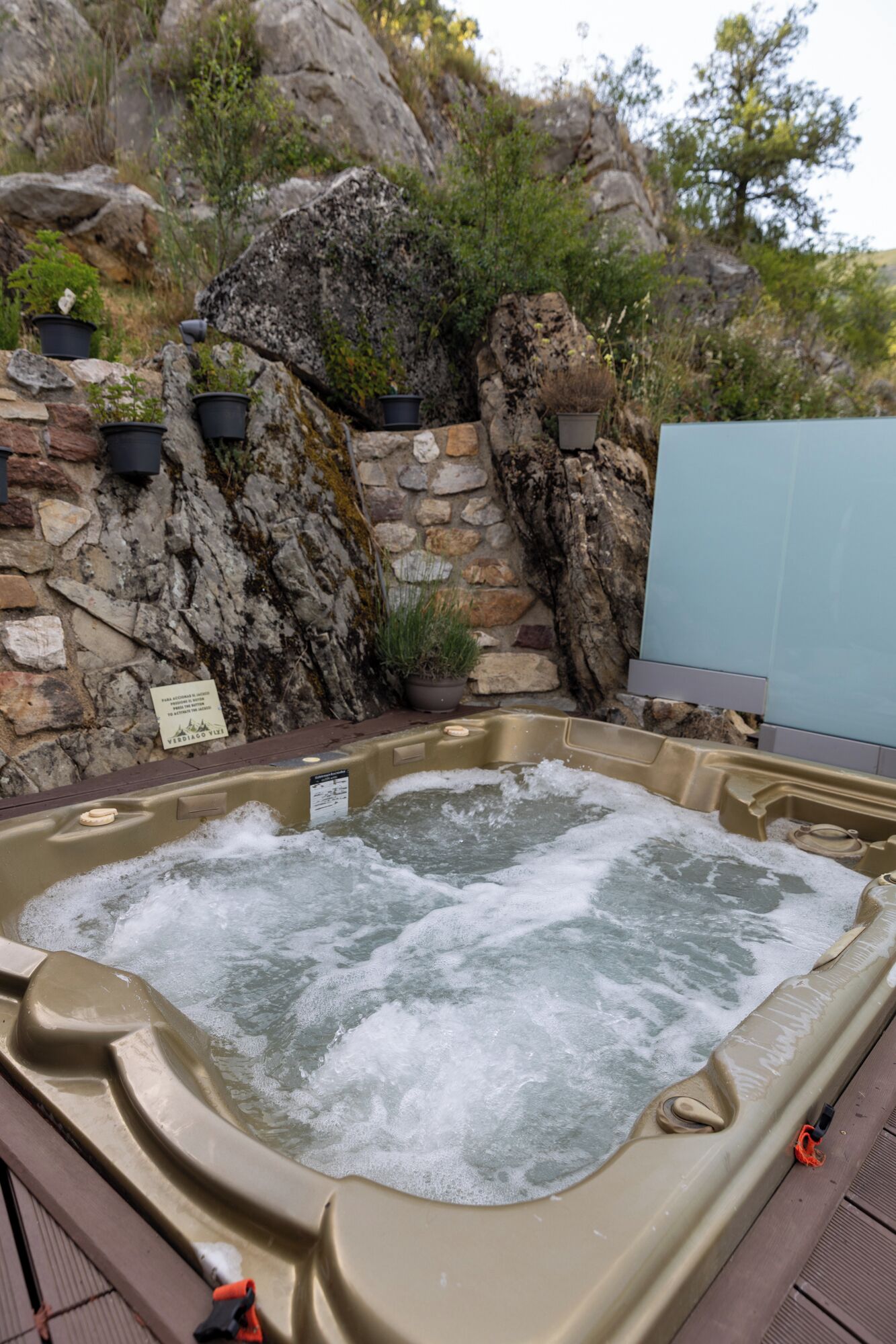 Ein Whirlpool, umgeben von einer Steinmauer mit Blumentöpfen.