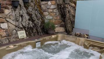 Ein Whirlpool, umgeben von einer Steinmauer mit Blumentöpfen.