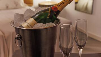 A minibar with a bottle of champagne and ice, and two empty glasses on a wooden table in a hotel room.