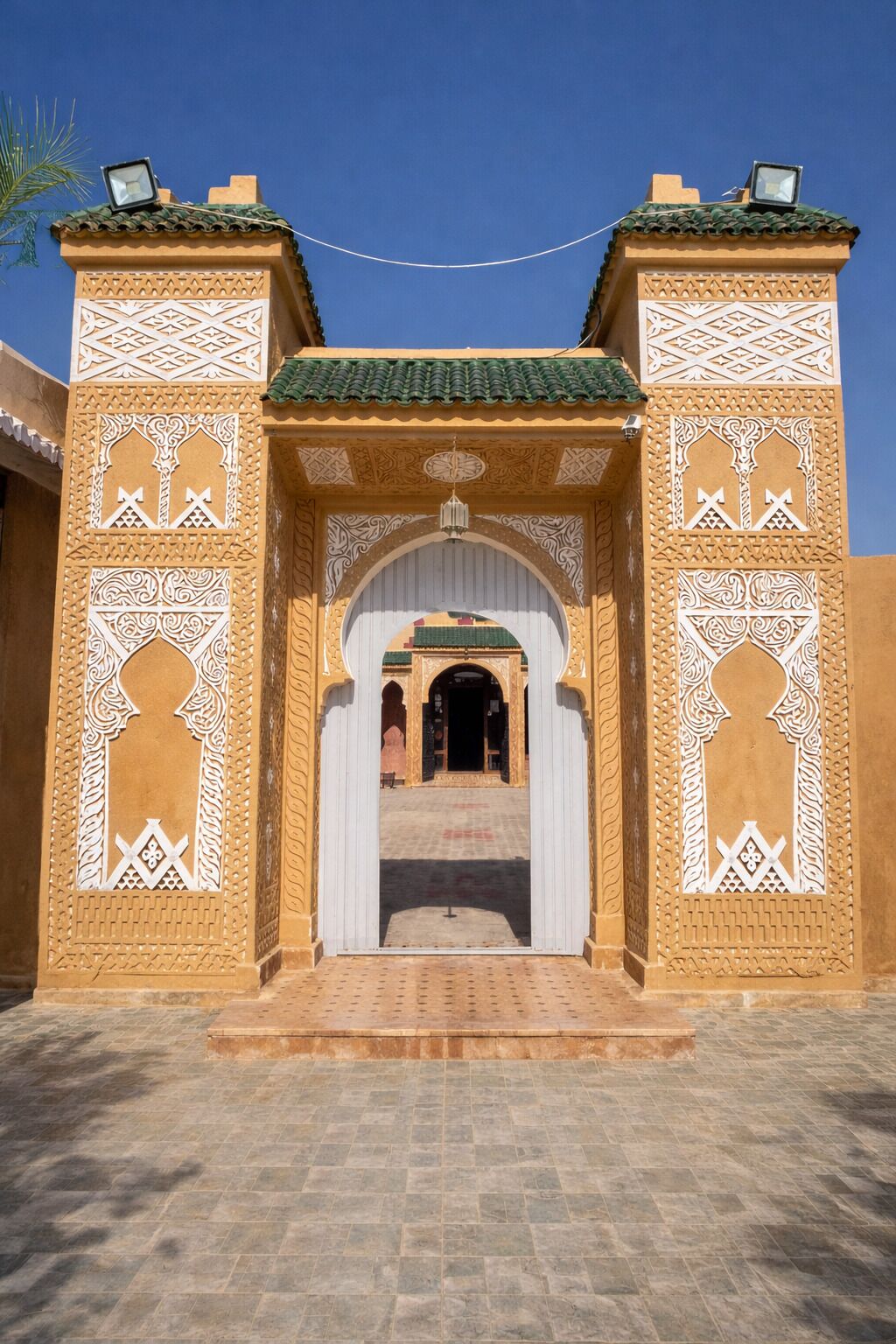 Un arco tradicional con intrincados diseños blancos y techo de tejas, que da paso a un patio interior.