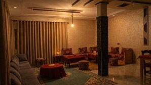 Une chambre d’hôtel avec un canapé, deux tables, un tapis et une grande colonne.