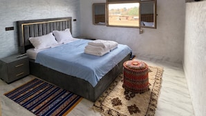 Une chambre moderne avec un lit, des tables de chevet, une fenêtre et un luminaire au plafond.