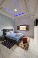 Un dormitorio moderno con cama, mesitas de noche, ventana y luz de techo.