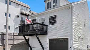 Un edificio a due piani con un balcone, un garage e una bandiera americana.