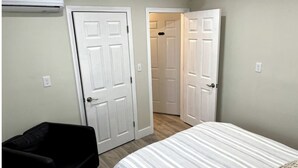 Una camera da letto con un letto, una sedia nera e due porte bianche che danno su altre stanze.