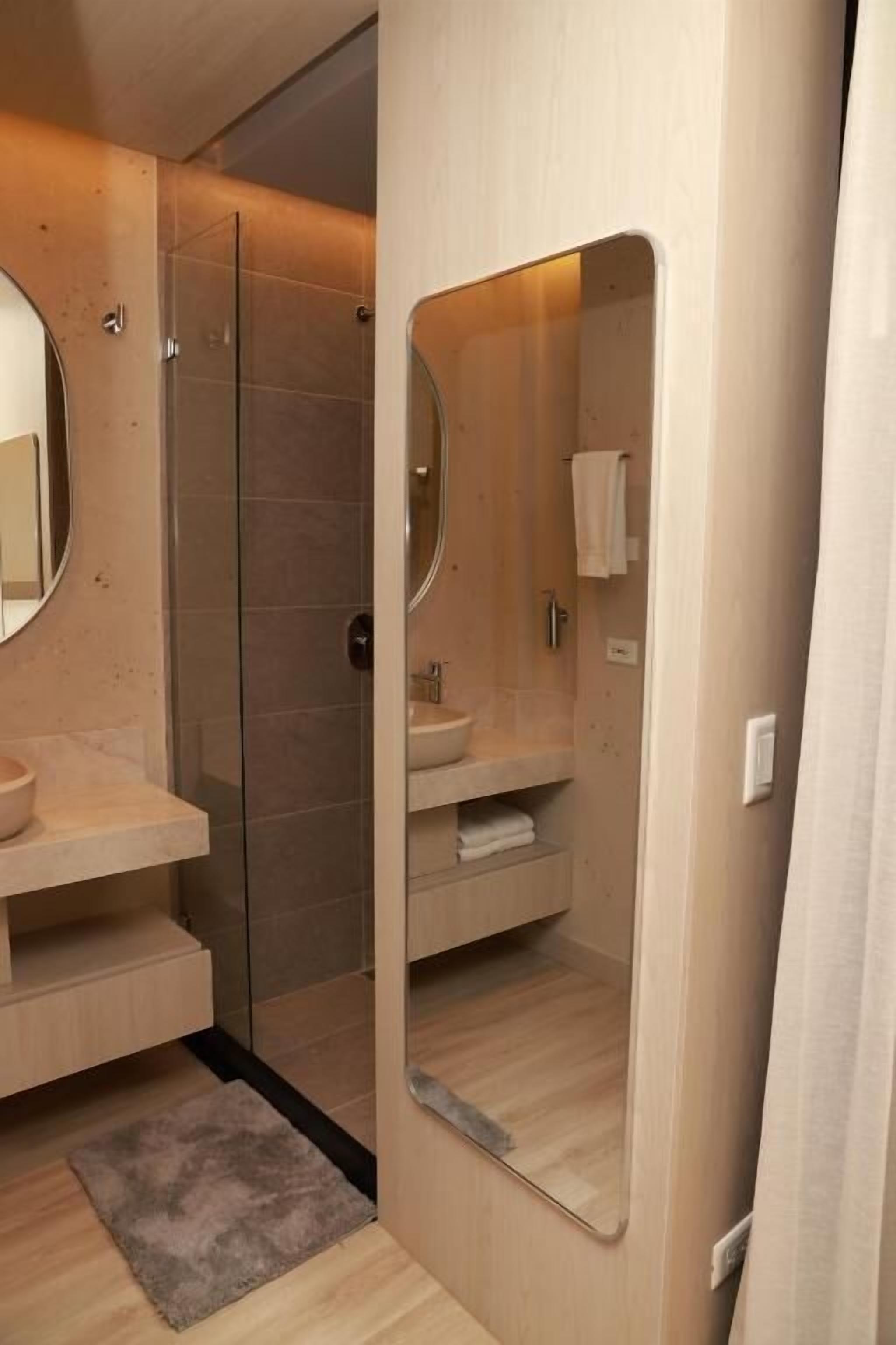 Une salle de bain moderne avec une douche à parois de verre, un meuble-lavabo en bois et un grand miroir.