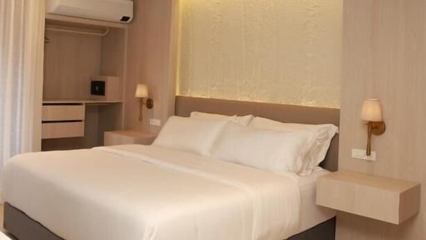 A modern hotel room with a large bed, bedside tables, a wardrobe, and a ceiling-mounted air conditioner. - VPV SUITES & CASINO (Medellín)