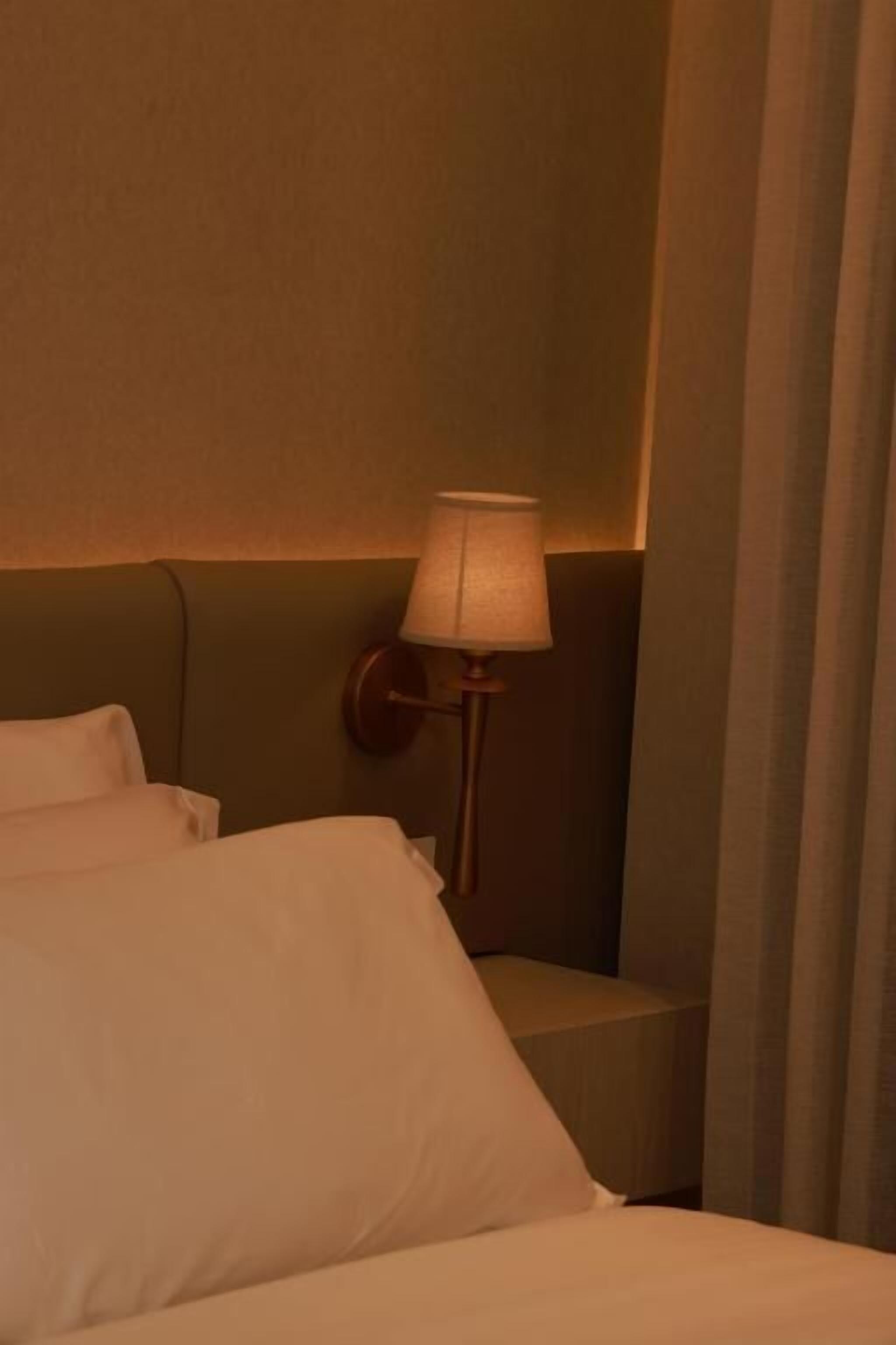 Une chambre d’hôtel avec un lit, une table de chevet et une lampe.