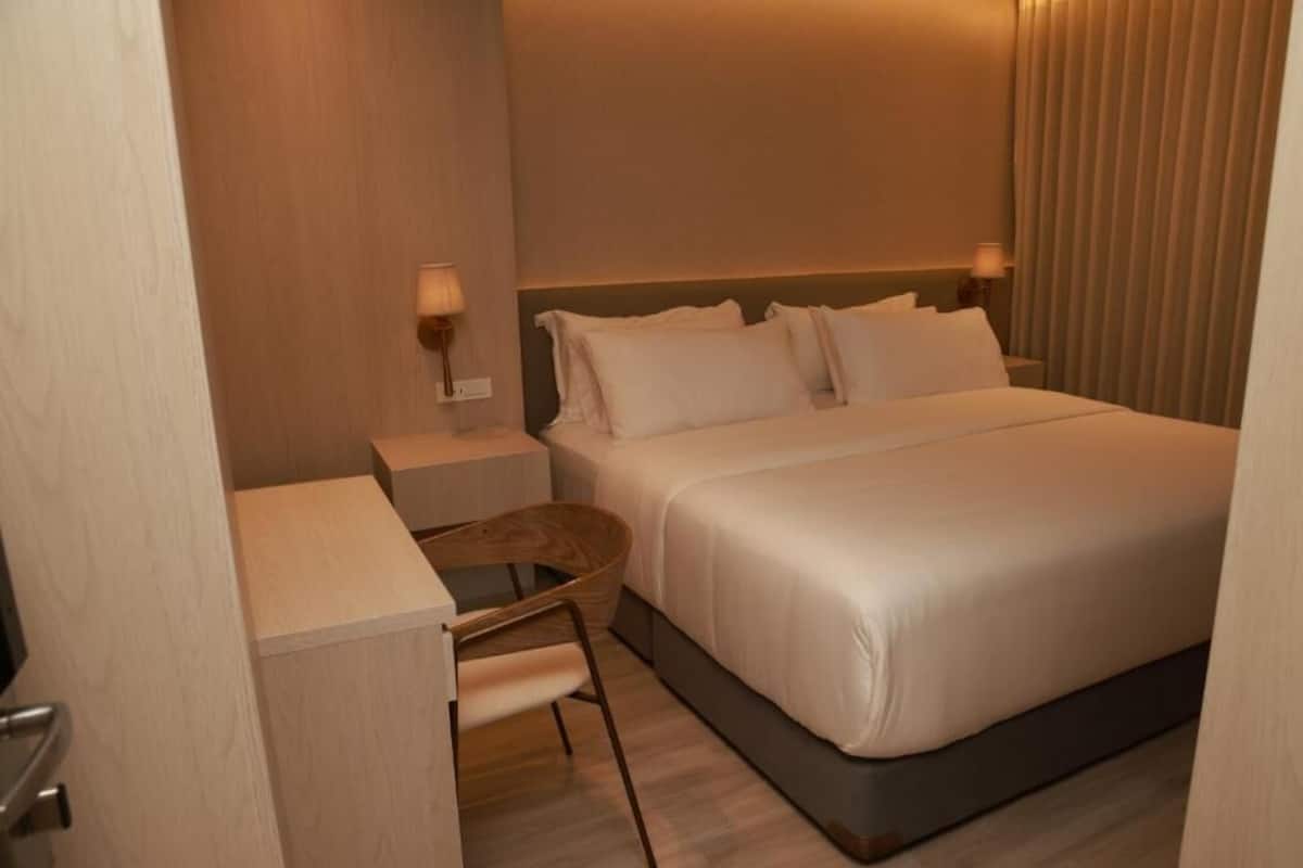 A hotel room with a bed, bedside tables, a chair, and a lamp.
