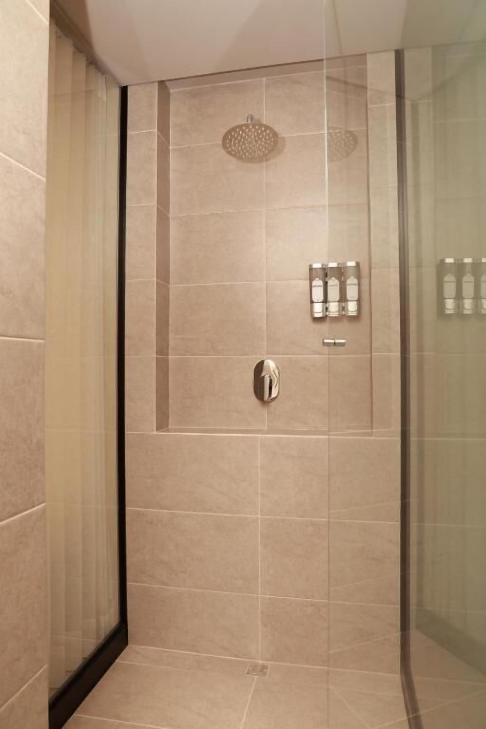 A modern bathroom with a glass shower enclosure, a built-in toilet, and a wall-mounted towel rack.