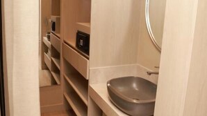 A modern bathroom with a built-in sink, mirror, and storage shelves. - VPV SUITES & CASINO (Medellín)