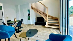 Ein modernes Wohnzimmer mit einer Holztreppe, einem Essbereich und einem großen Fenster.
