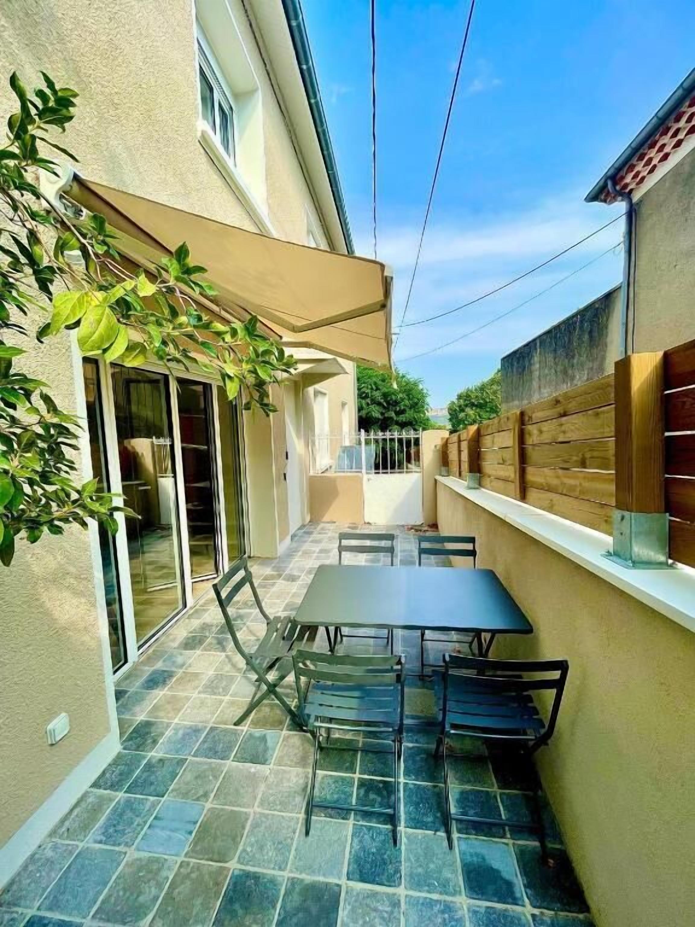 Une terrasse avec une table et des chaises, une porte-fenêtre coulissante et une clôture en bois.