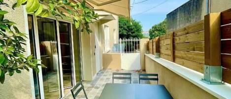 A patio with a table and chairs, a sliding glass door, and a wooden fence.