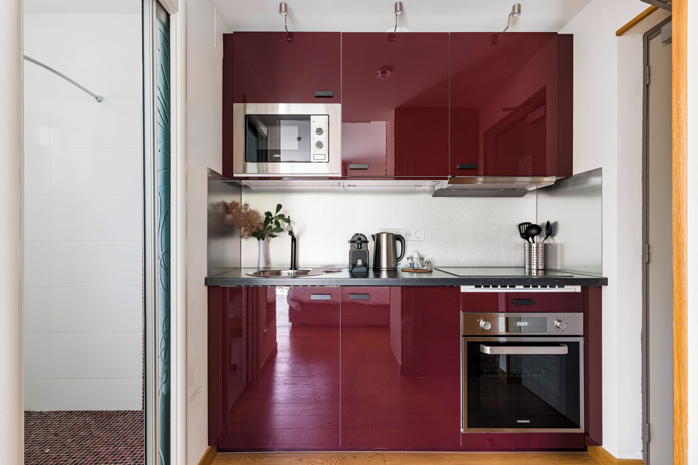 Una cucina compatta con forno a microonde, macchina del caffè e forno.