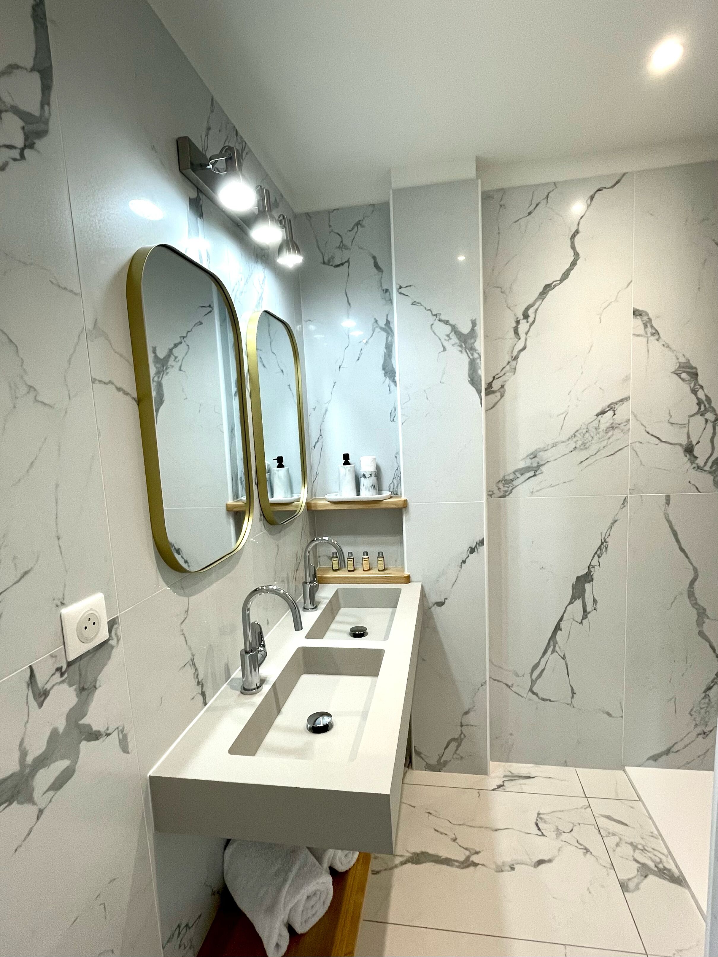 A bathroom with two sinks, a mirror, and a shower.