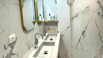 A bathroom with two sinks, a mirror, and a shower.