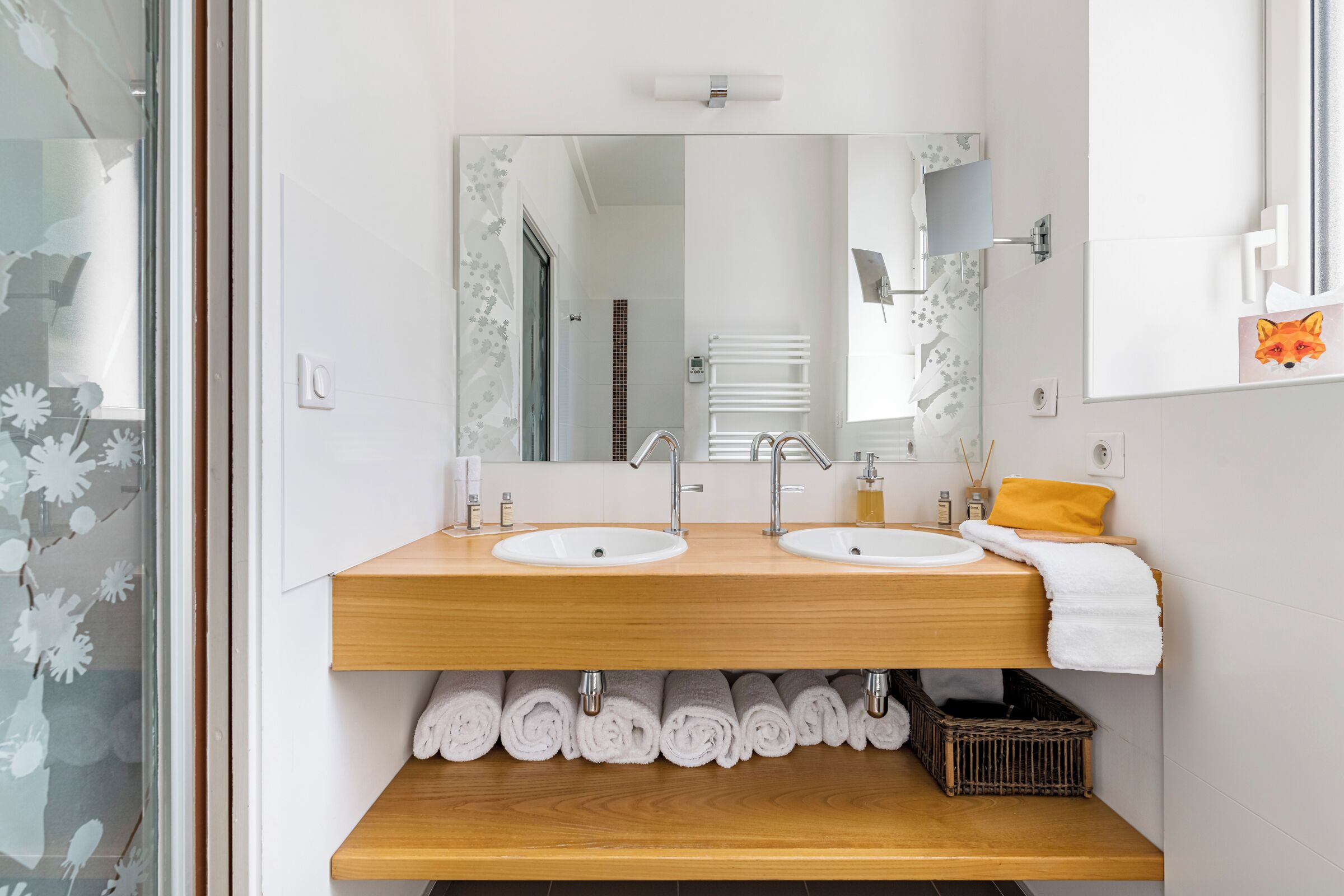 Un baño moderno con dos lavamanos, un espejo y un mueble de tocador de madera.
