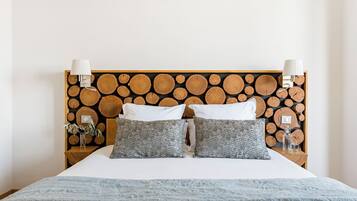 A bed with a wooden headboard, two white pillows, two gray patterned pillows, and a blue blanket.