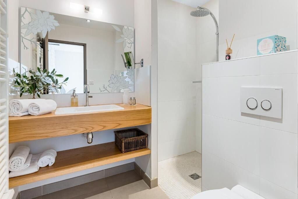 A modern bathroom with a wooden vanity, a large mirror, and a shower area.