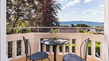 Un balcon avec deux chaises et une table, un vase et un livre.